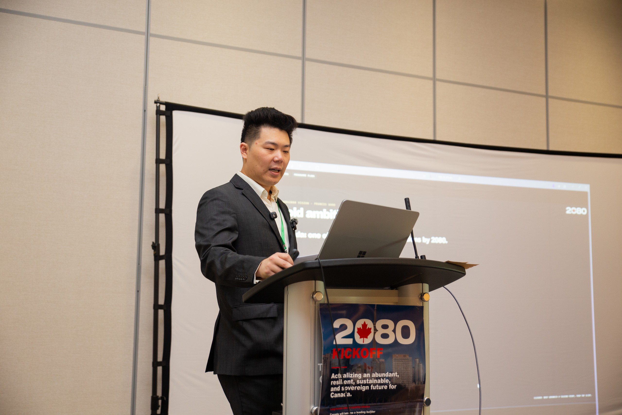 Francis Wang speaking at the podium. The slide behind him reads bold ambition by 2080.
