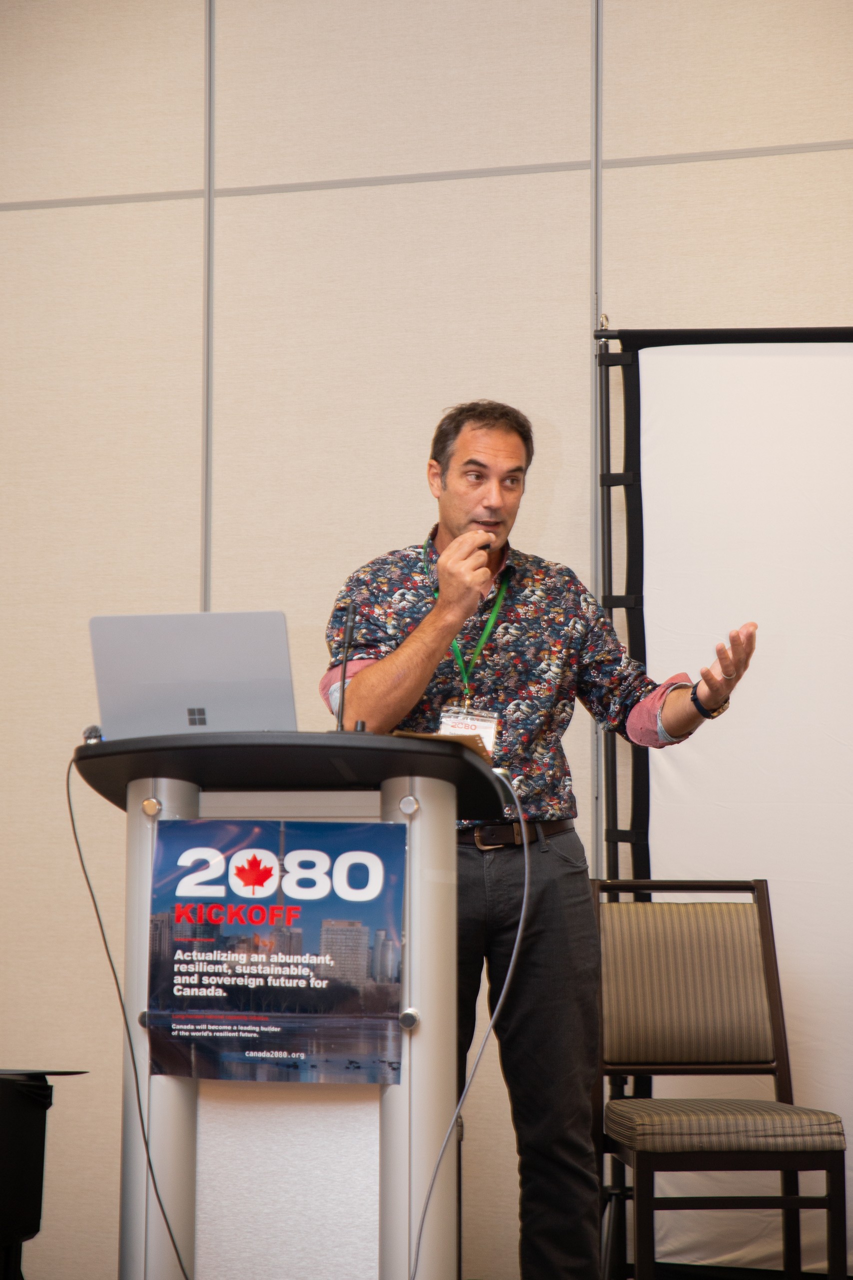 Sebastien Gendron speaking at the podium in a floral shirt.